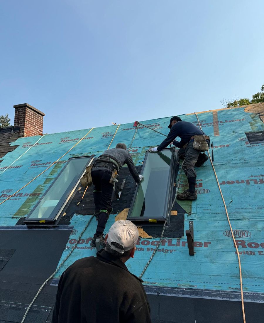 Well Roofing installers fitting VELUX skylights into a shingled roof